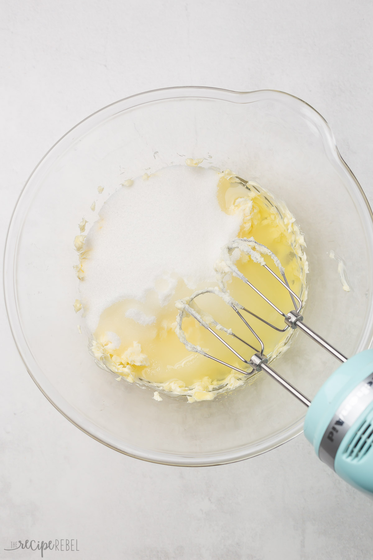 combining oil and sugar in a glass bowl for lemon cake.