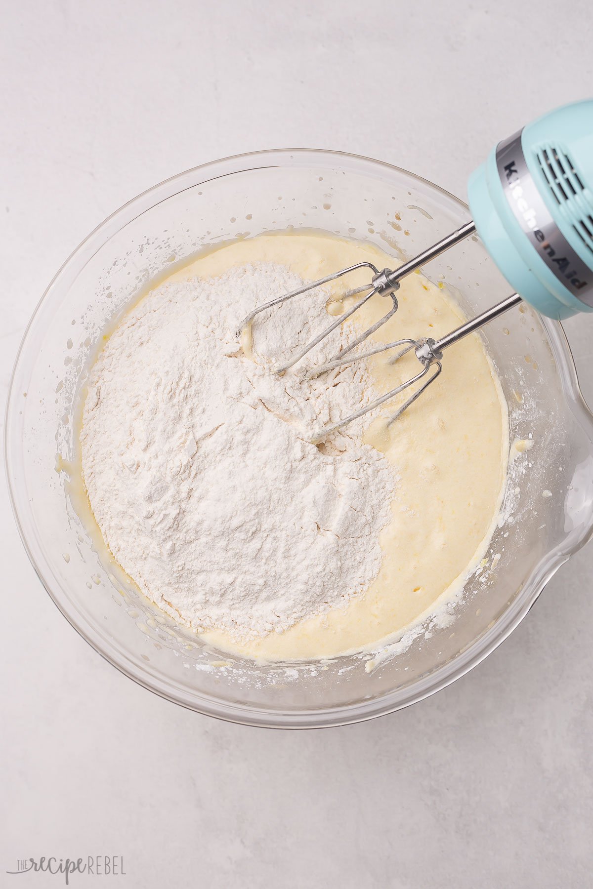 flour added to cake batter in glass bowl.