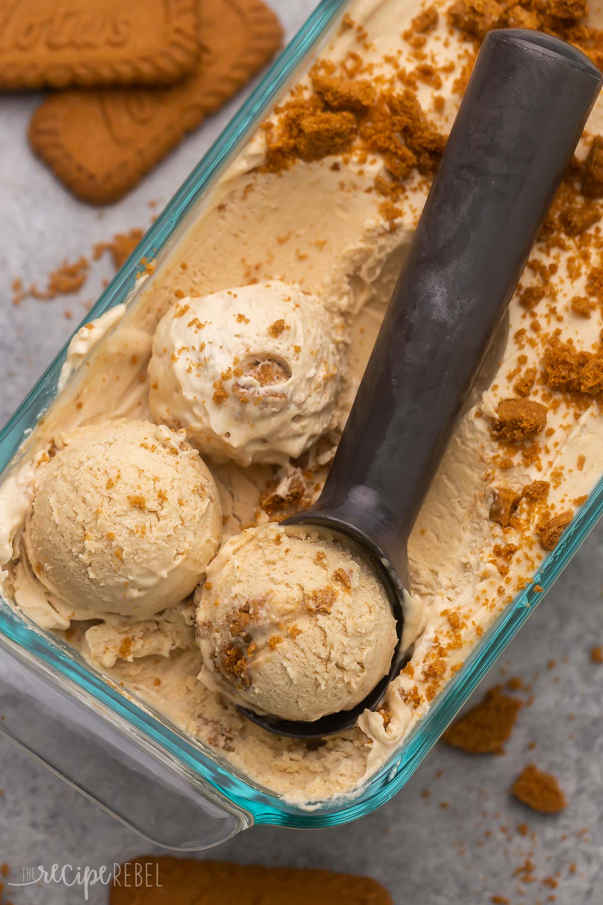 Top view of no churn Biscoff ice cream in a glass dish with an ice cream scoop in it. 