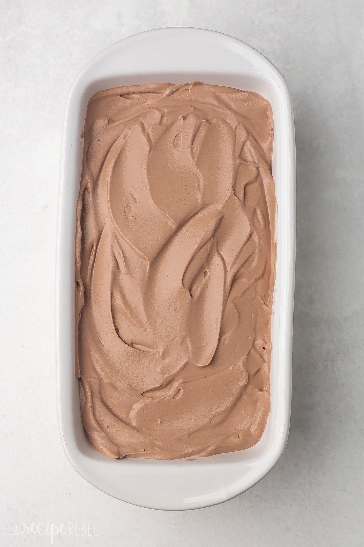 Top view of a white ice cream pan with unset chocolate ice cream in it. 