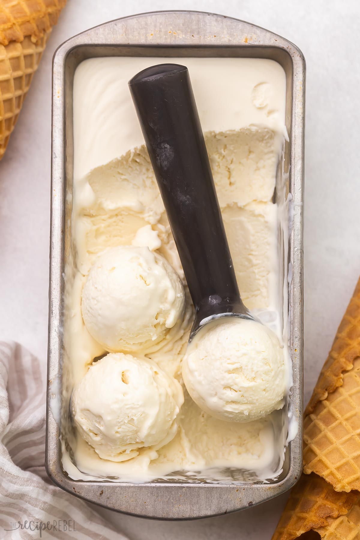 Top view of Vanilla Ice Cream in an ice cream tray being scooped with an ice cream scoop.