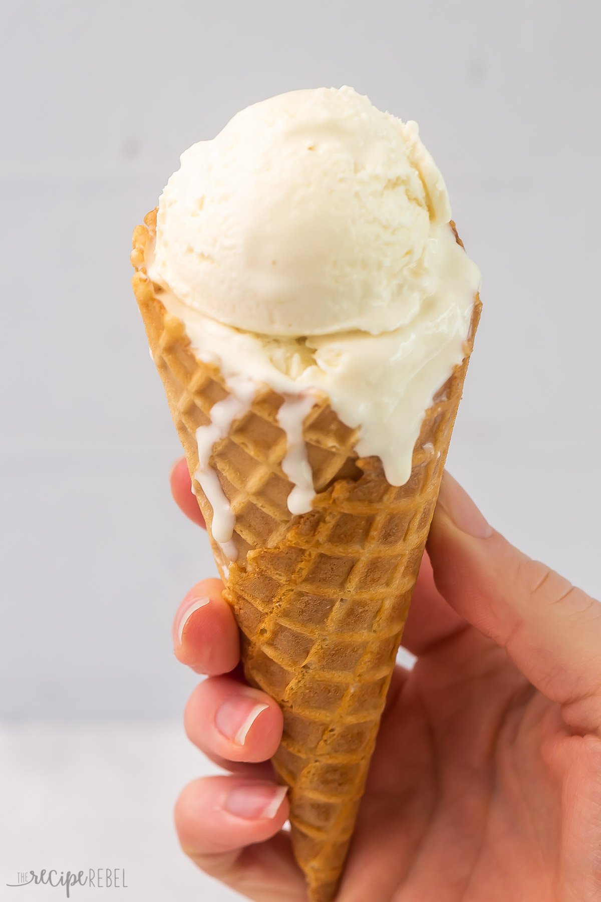 Close up of a waffle cone with a scoop of vanilla no churn ice cream in it. 