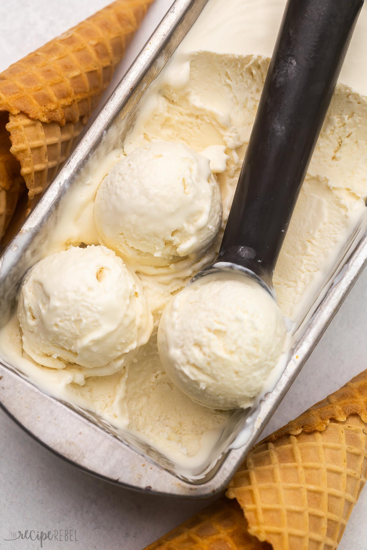 Top view of No Churn Ice Cream in an ice cream tray being scooped with an ice cream scoop. 