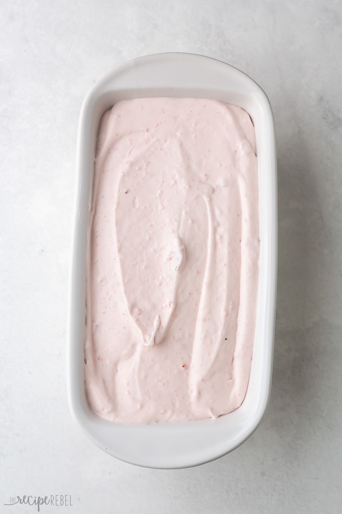 Top view of white rectangle dish with strawberry ice cream mixture in it.