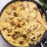 close up shot of cooked chicken meatballs and orzo in black frying pan.