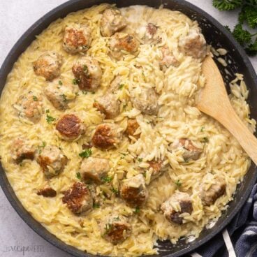 close up shot of cooked chicken meatballs and orzo in black frying pan.