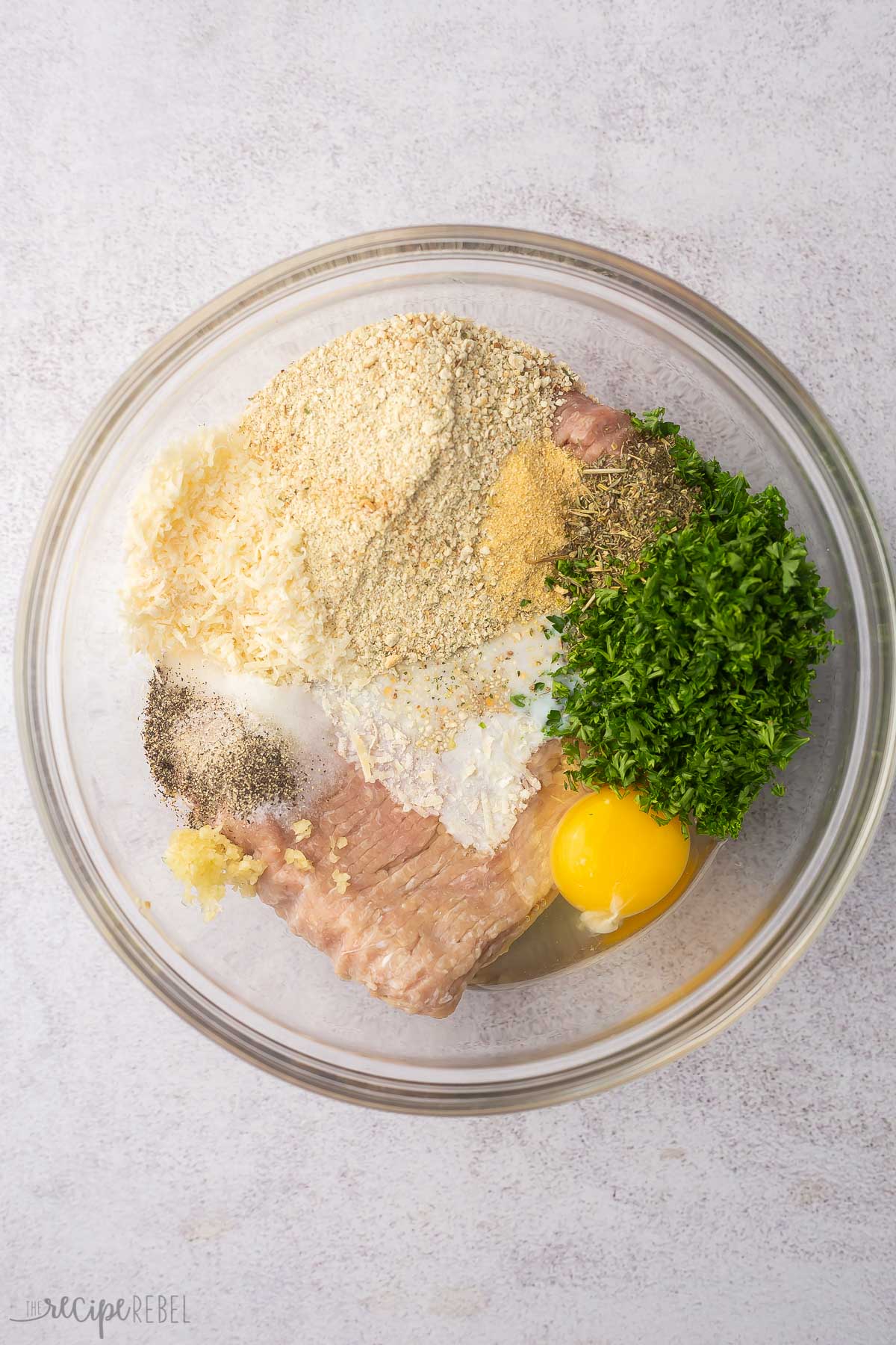 glass bowl filled with unmixed ingredients for chicken meatballs.