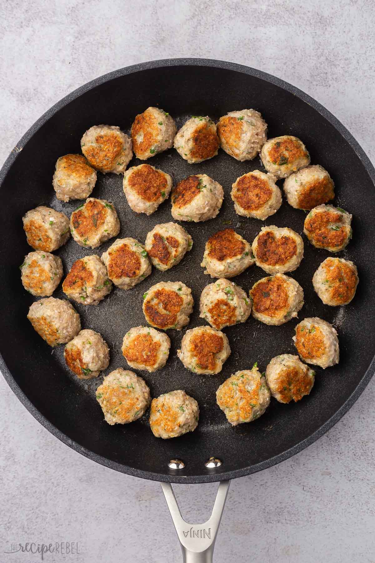 black frying pan filled with fried chicken meatballs .