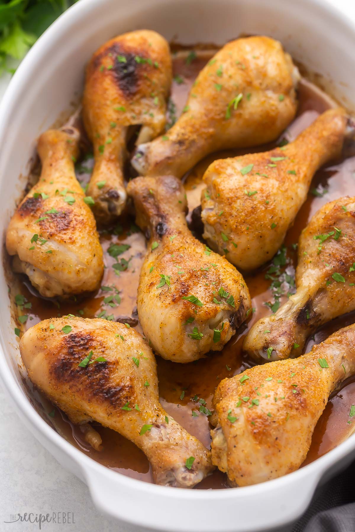 white baking dish with eight baked chicken drumsticks.