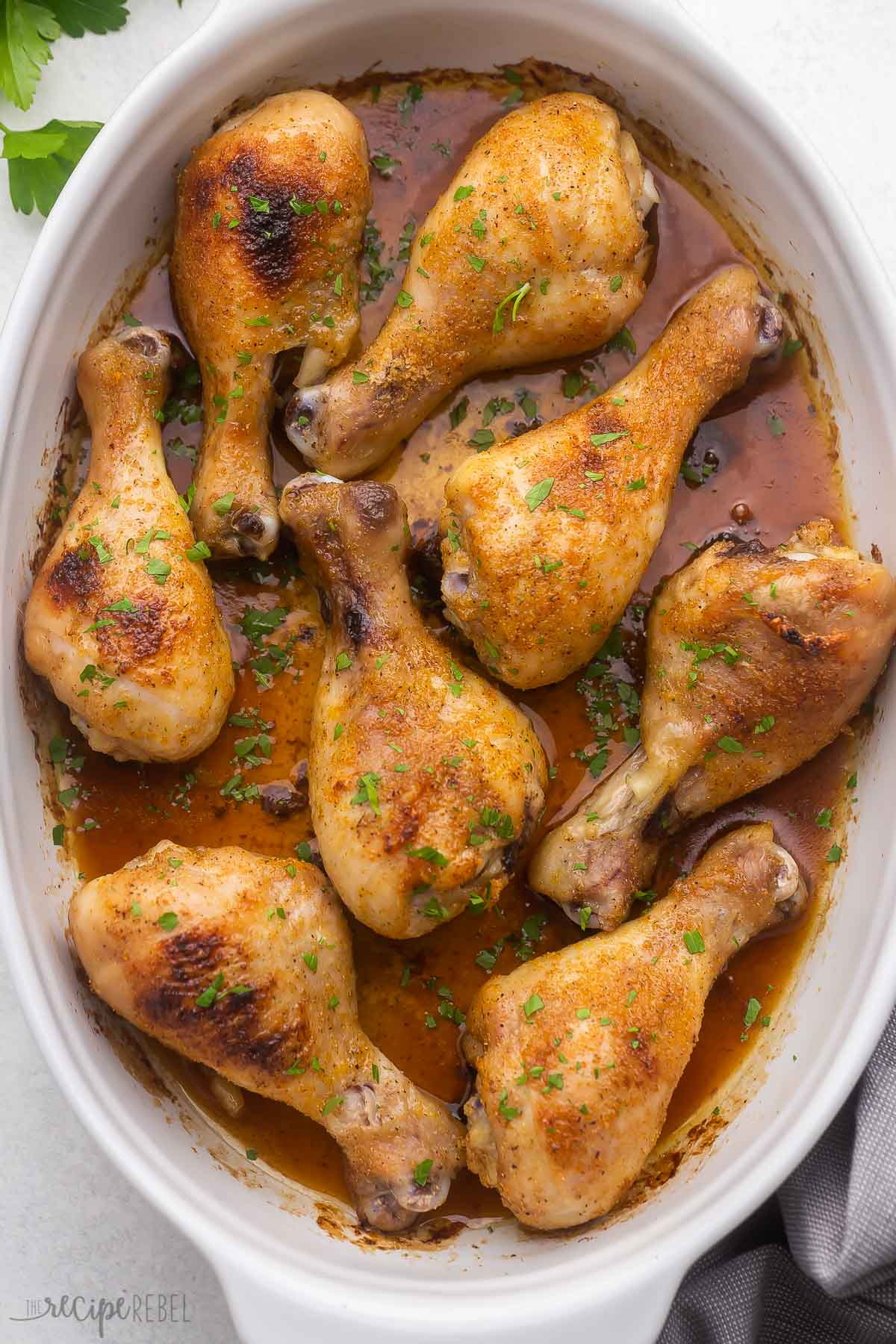 overhead shot of white dish filled with baked chicken drumsticks.