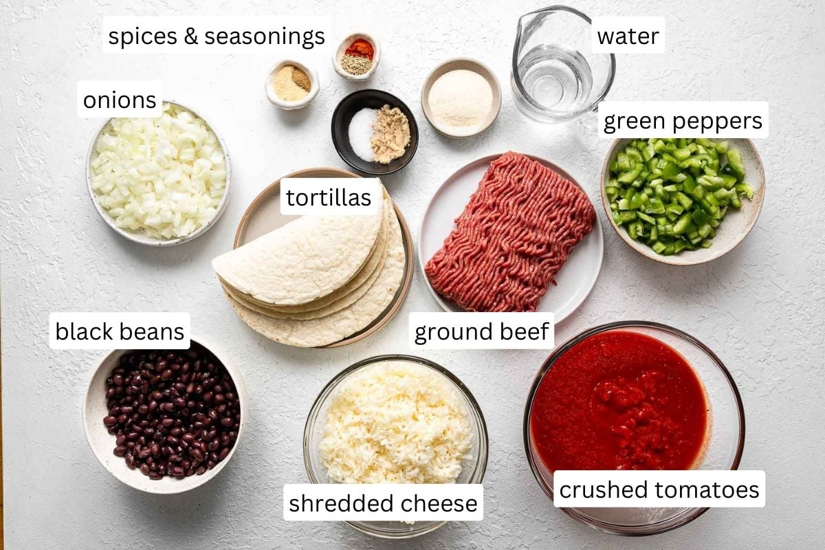 ingredients for beef enchiladas on a white surface.