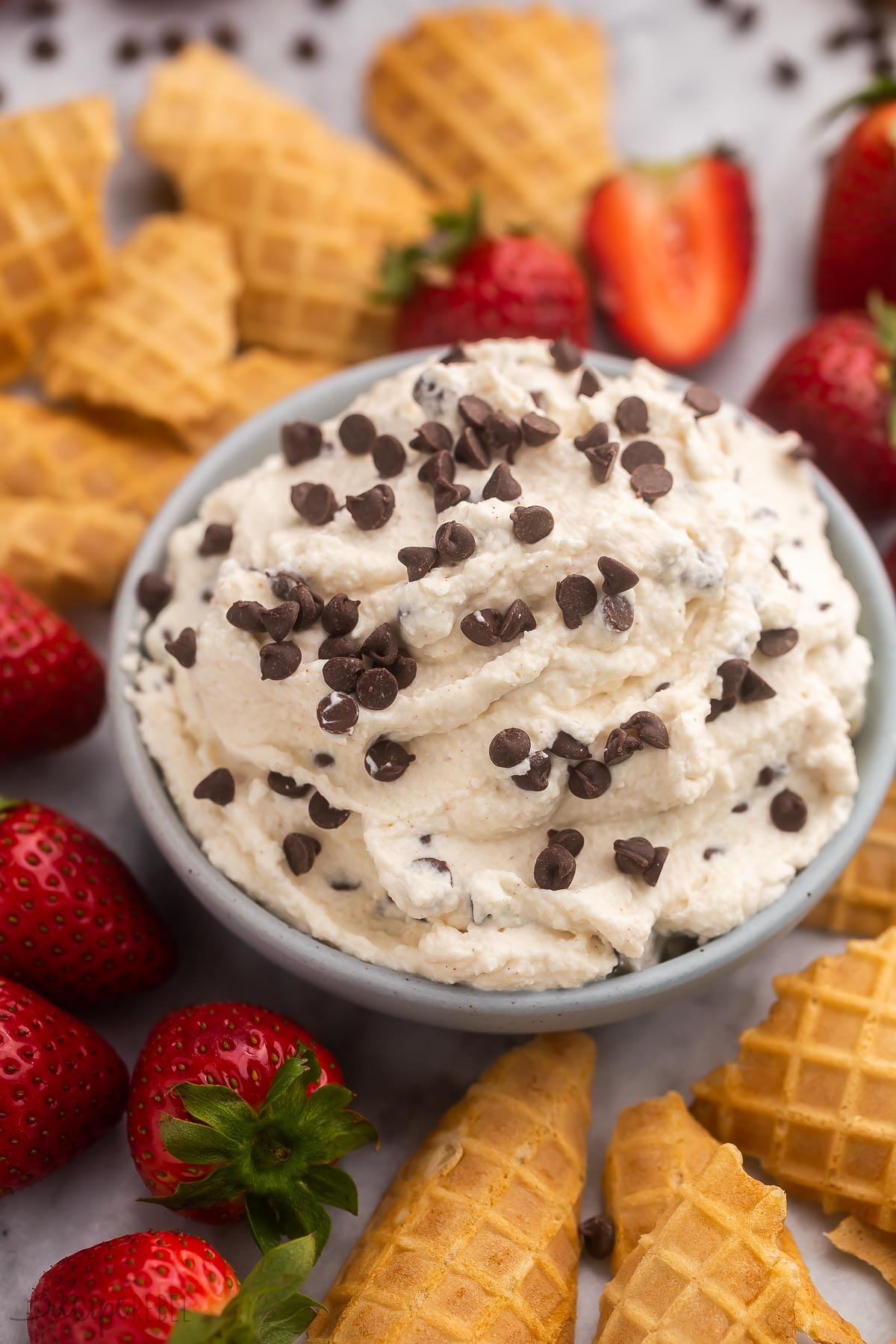 side view of cannoli dip in a grey bowl with chocolate chips on top.