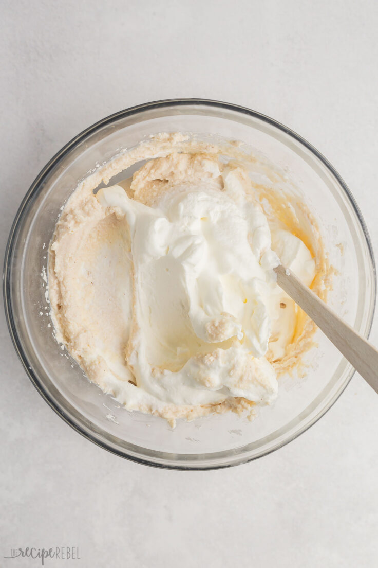 glass mixing bowl with ricotta mixture and whipped cream added.