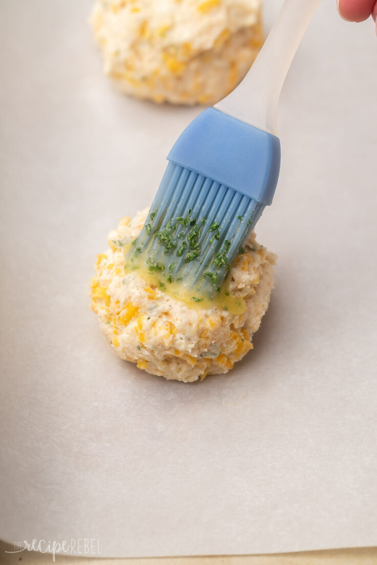 a biscuit on parchment paper being brushed with butter.