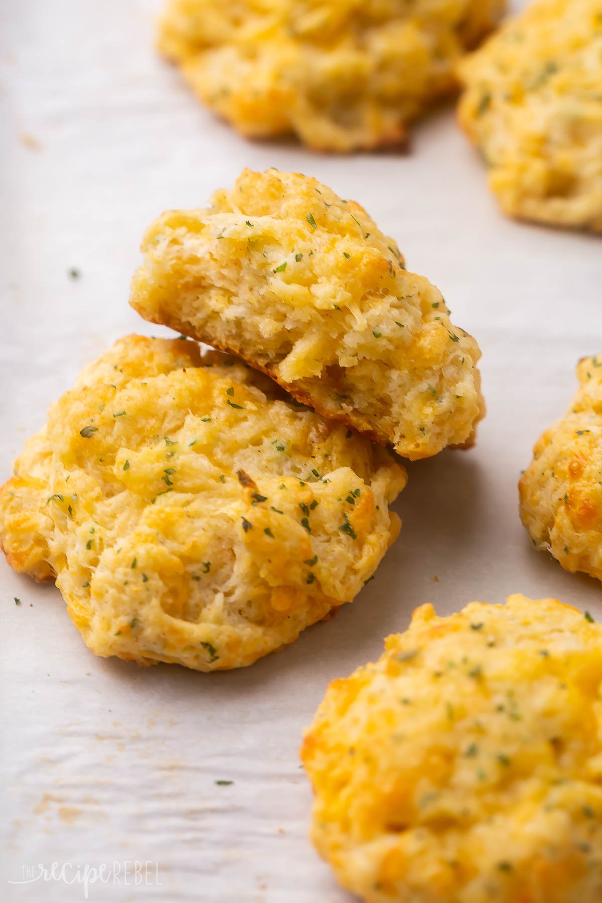 a few cheddar bay biscuits lying on parchment paper.