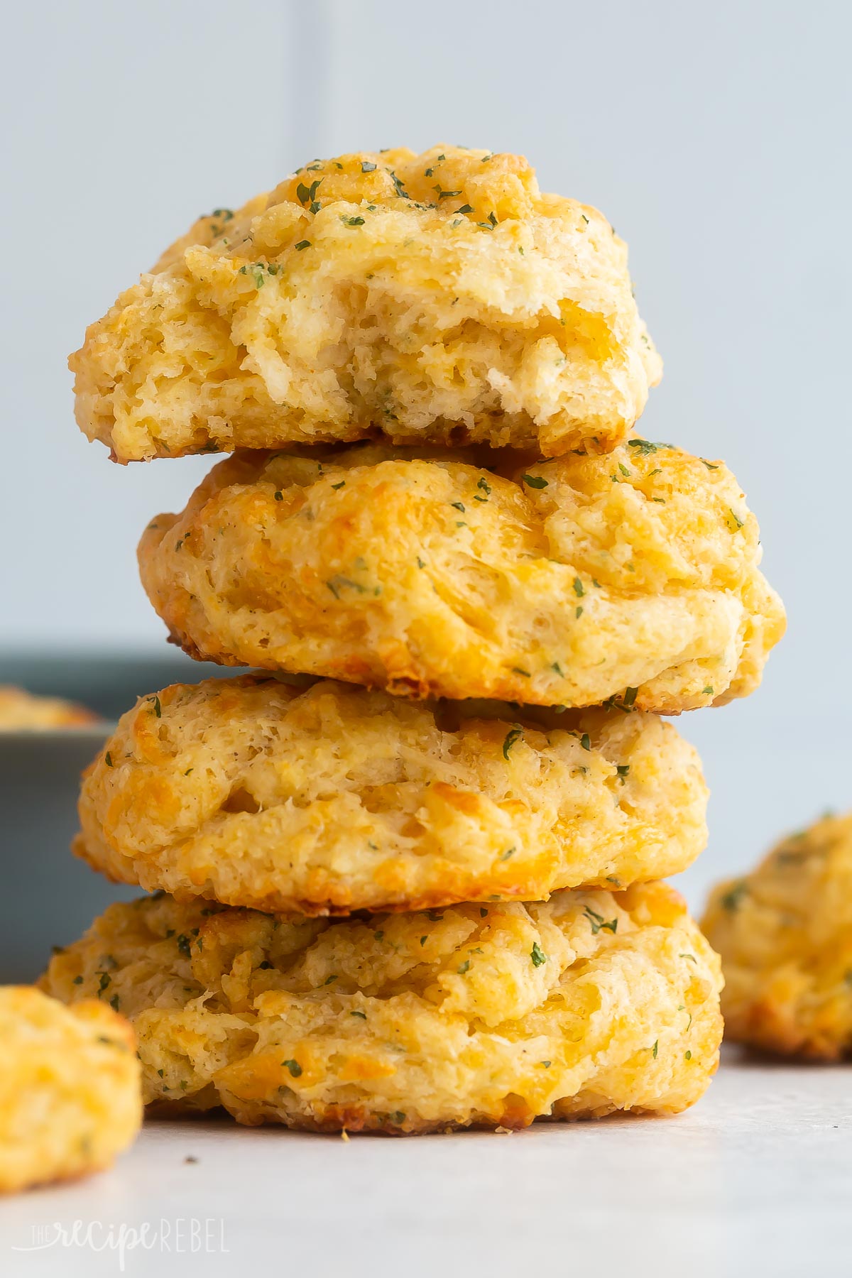 These Copycat Cheddar Bay Biscuits will be one of the best things to grace your dinner table! Made with homemade biscuit dough topped with garlic butter, these delicious biscuits are baked to perfection with a crisp outer while remaining soft and fluffy on the inside! #biscuits #baking #recipes | biscuit recipe | cheese biscuits | cheddar biscuit | drop biscuits | easy biscuits four golden cheddar bay biscuits stacked on top of each other.