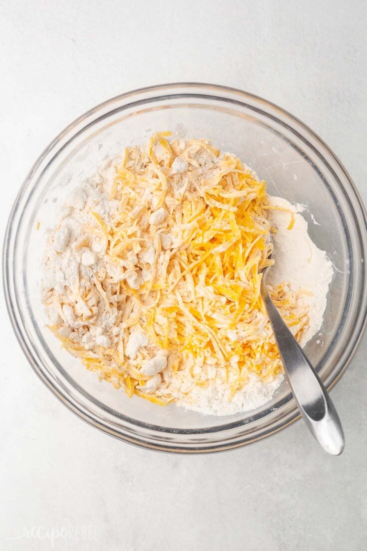 cheese on top of dry ingredients in glass mixing bowl.