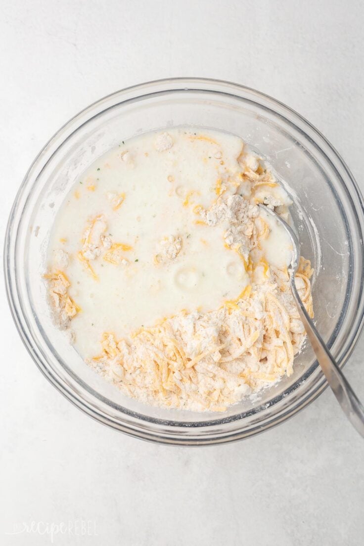 glass mixing bowl and spoon with buttermilk added to ingredients.