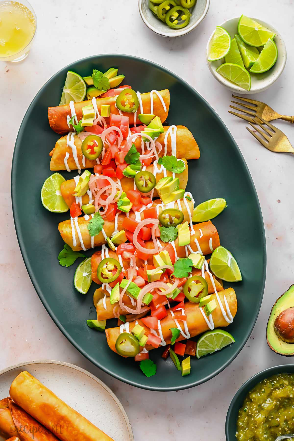 overhead view of a platter of chicken taquitos surrounded with toppings.