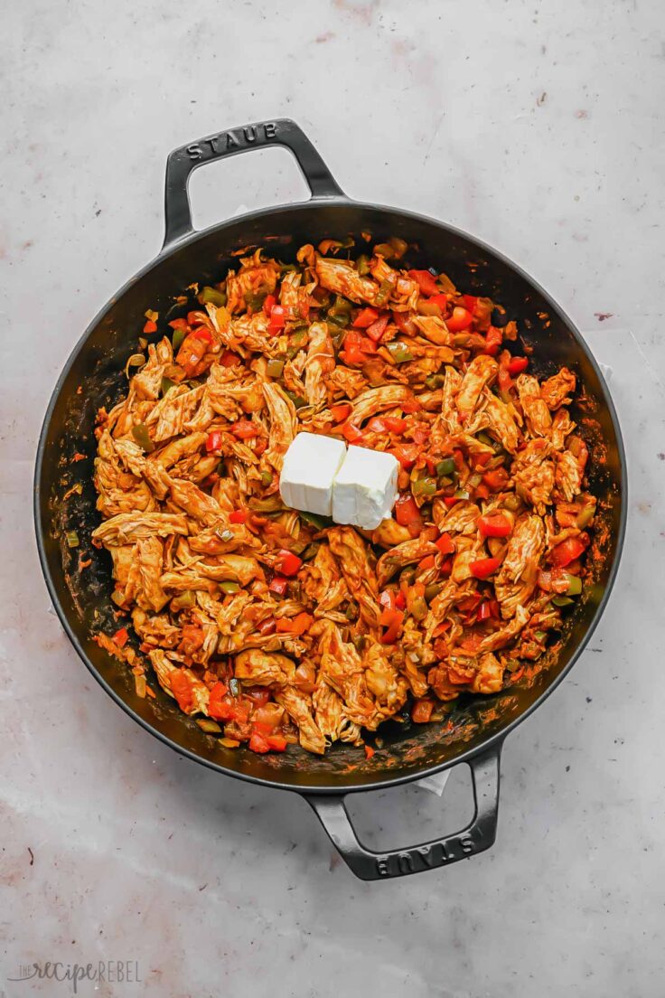 cooked chicken and vegetables in pan with cream cheese added on top.