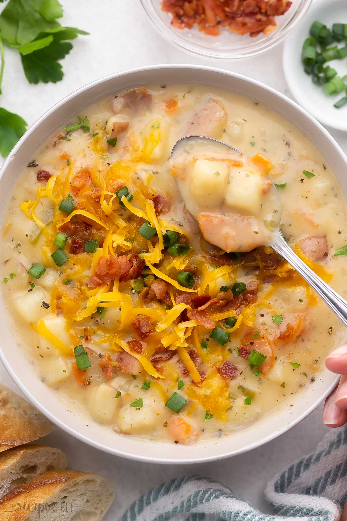 overhead shot of a bowl of potato soup topped with cheese, green onions, and bacon.