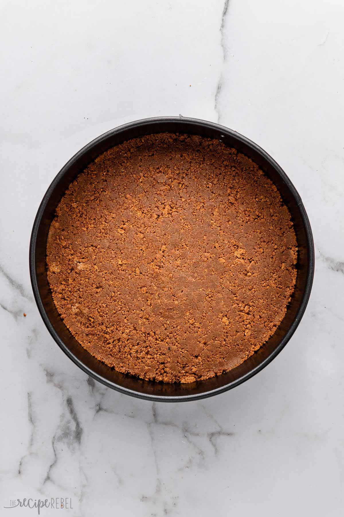 overhead view of a black spring form pan with cake crust pressed in.