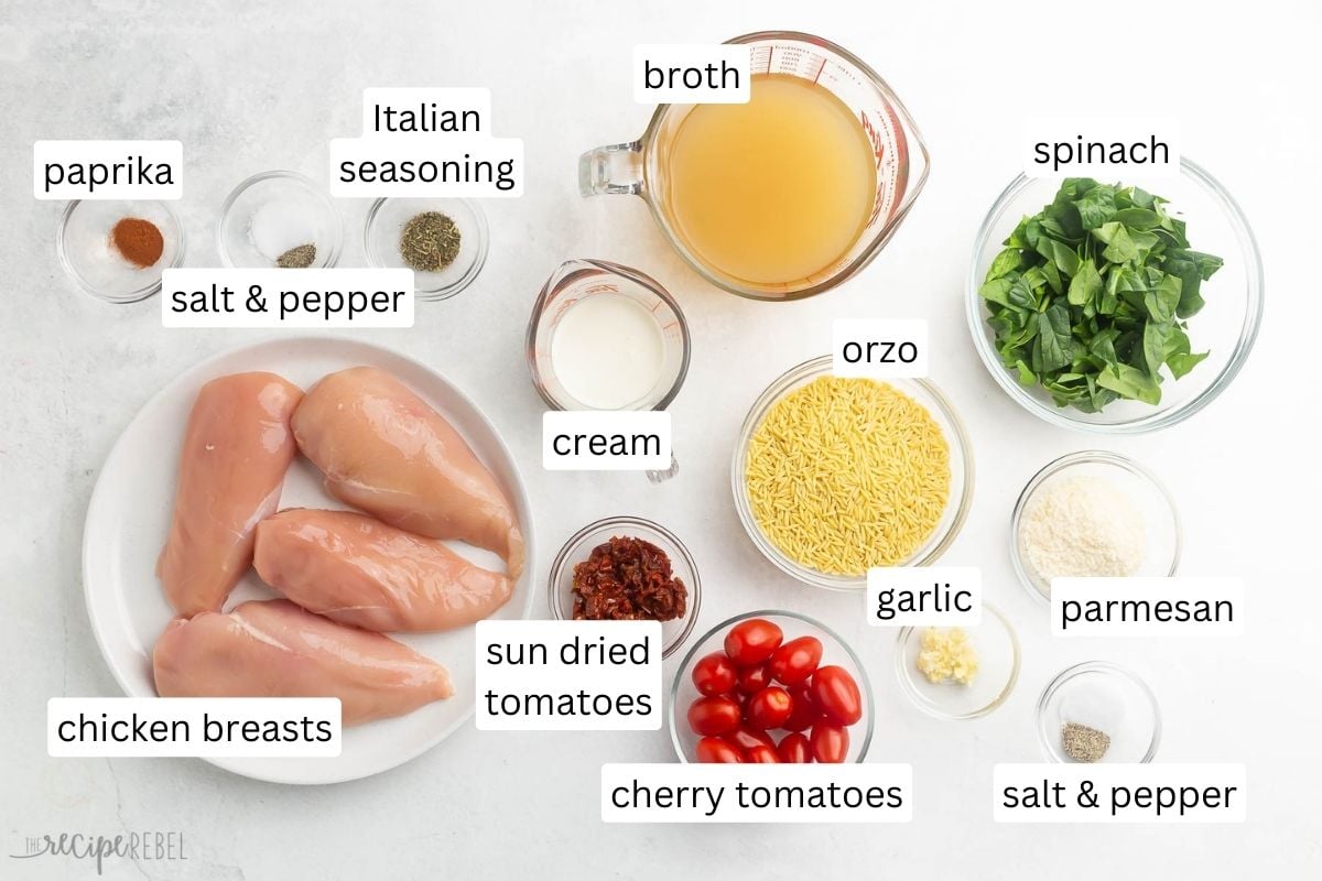 ingredients for tuscan orzo with chicken in glass bowls on grey surface.