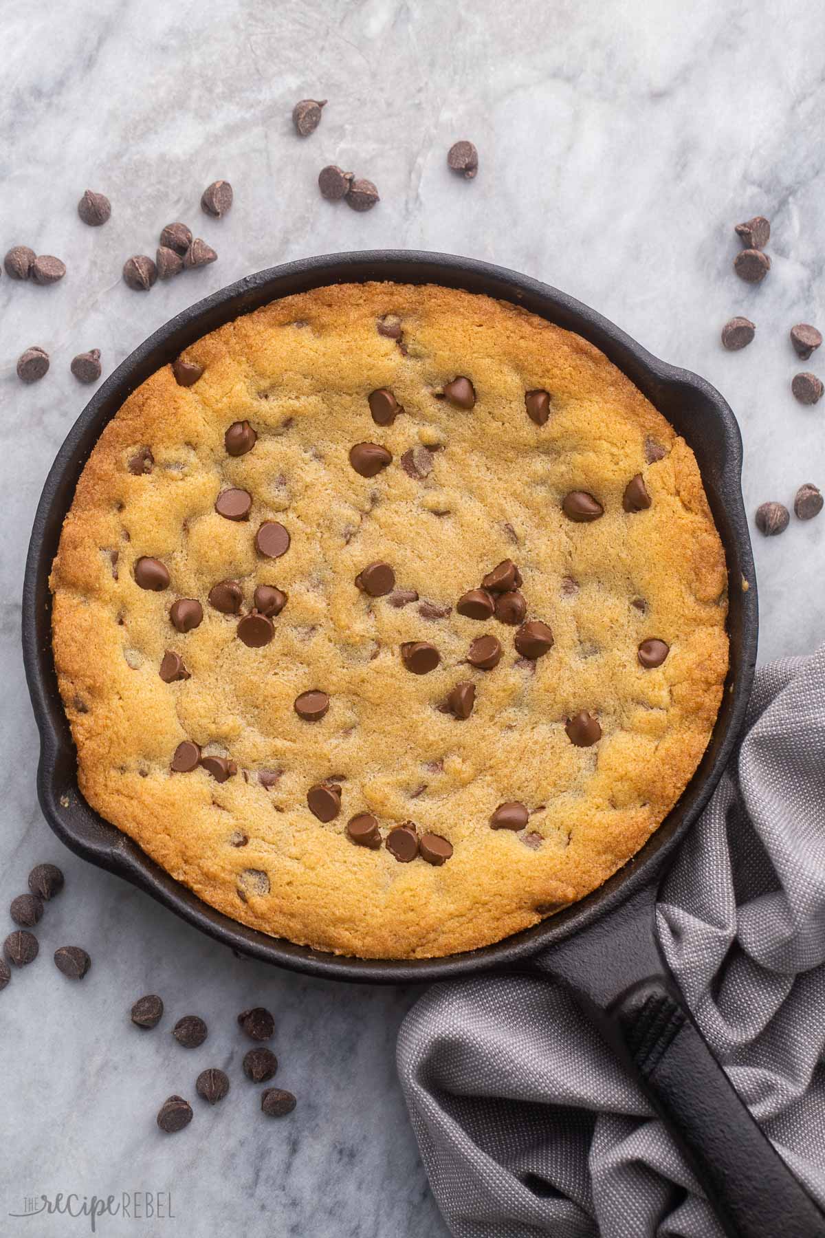 overhead shot of baked skillet cookie in pan surrounded by chocolate chips.