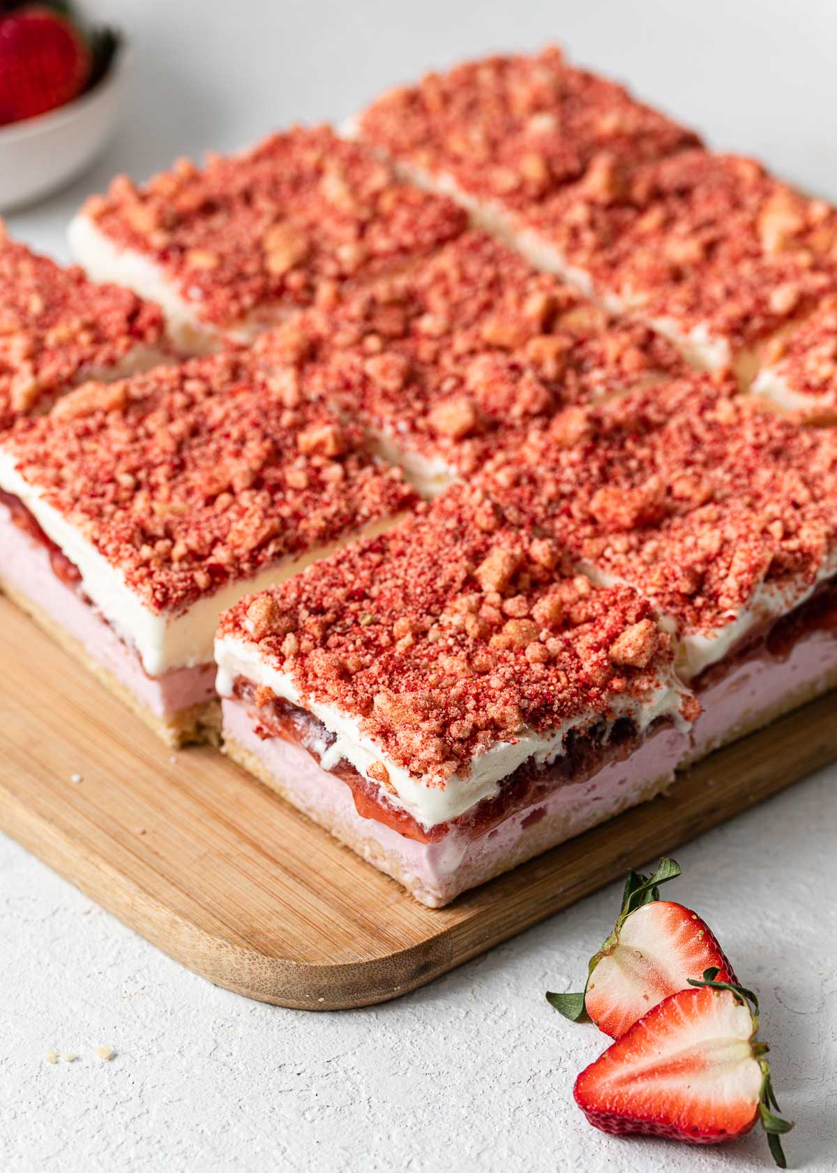 cutting board full of strawberry shortcake ice cream bars with strawberries beside.