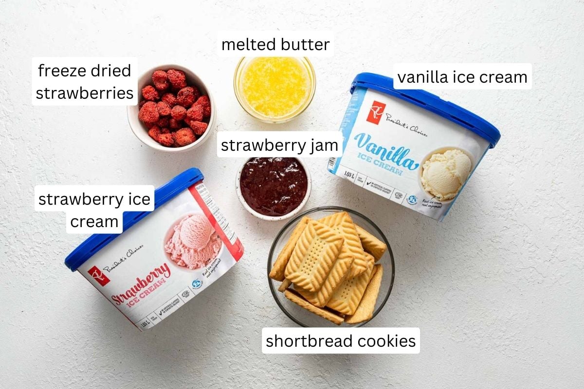 Top view of ingredients for strawberry shortcake ice cream bars on white surface.