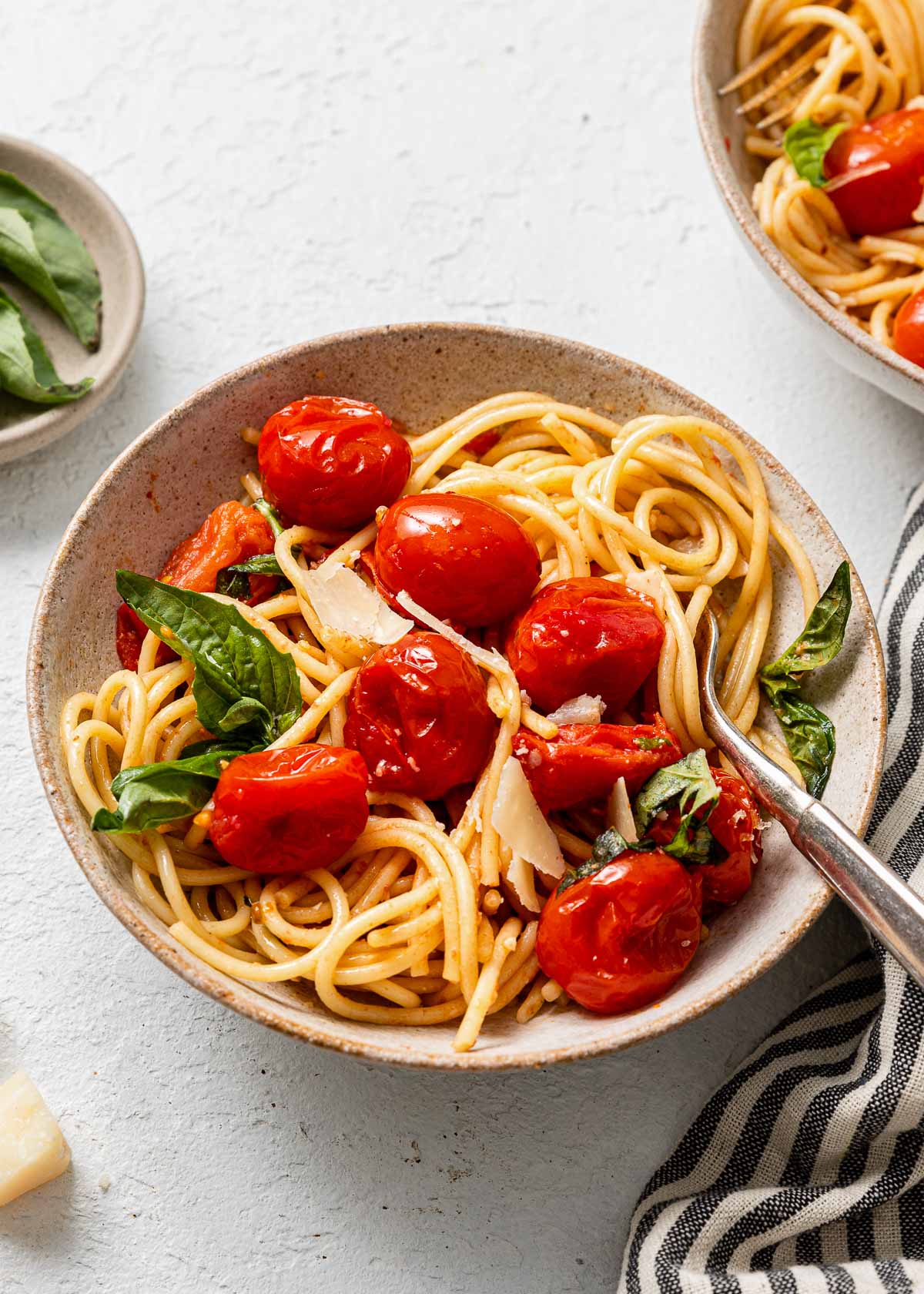 a full bowl of tomato basil pasta with a fork in it.