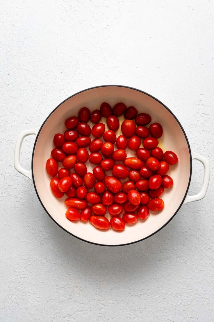 white pot with cherry tomatoes on a white surface.