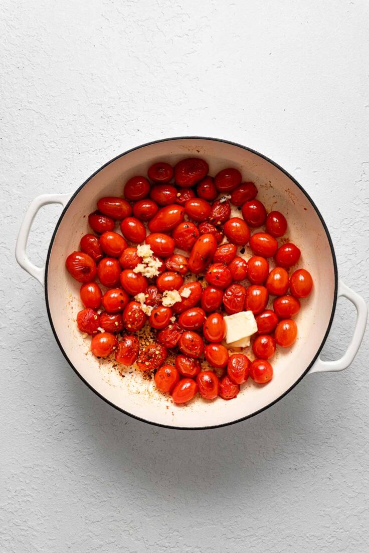 cherry tomatoes with spices and butter in white pot.