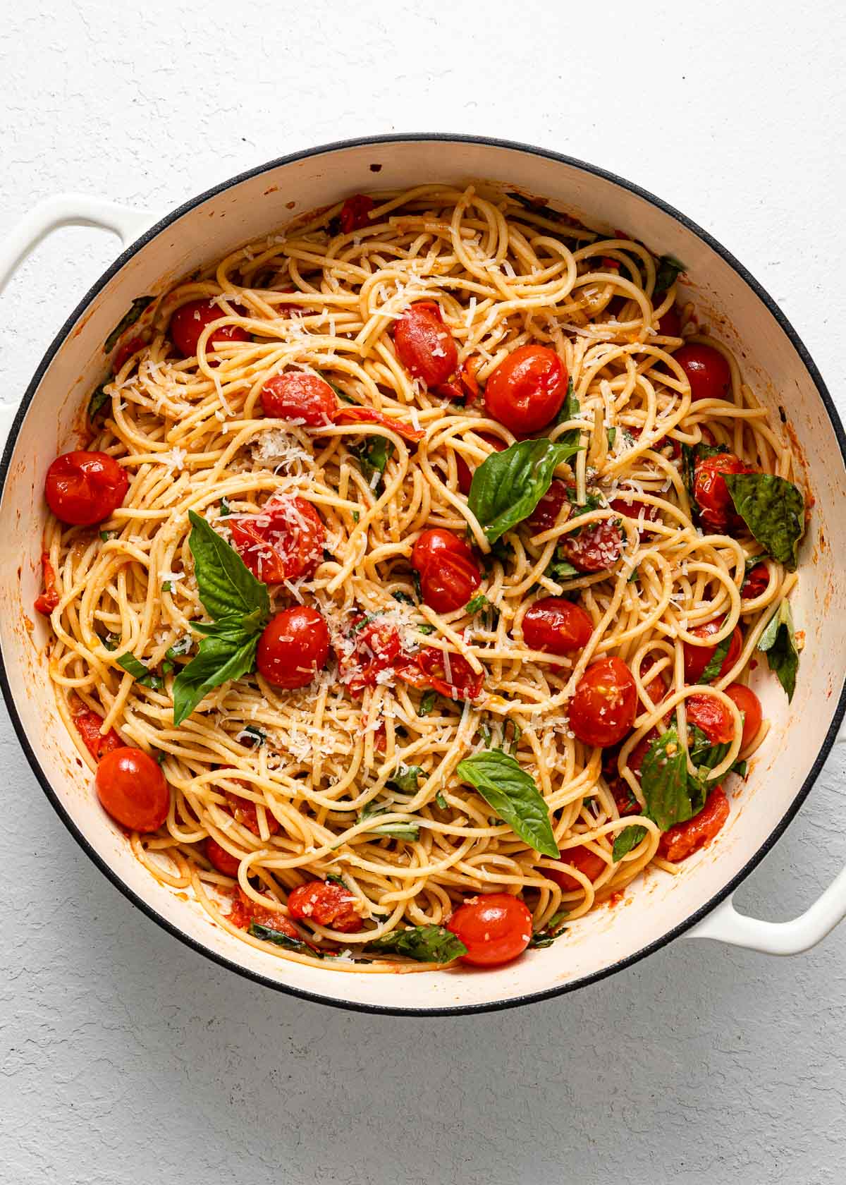 overhead view of a full pot of tomato basil pasta garnished with parmesan.