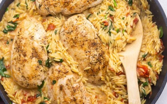close up shot of tuscan orzo and chicken in black pan.