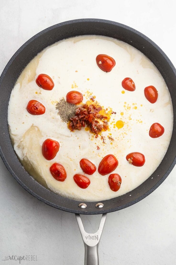 overhead shot of frying pan with cream, broth, spices and tomatoes.