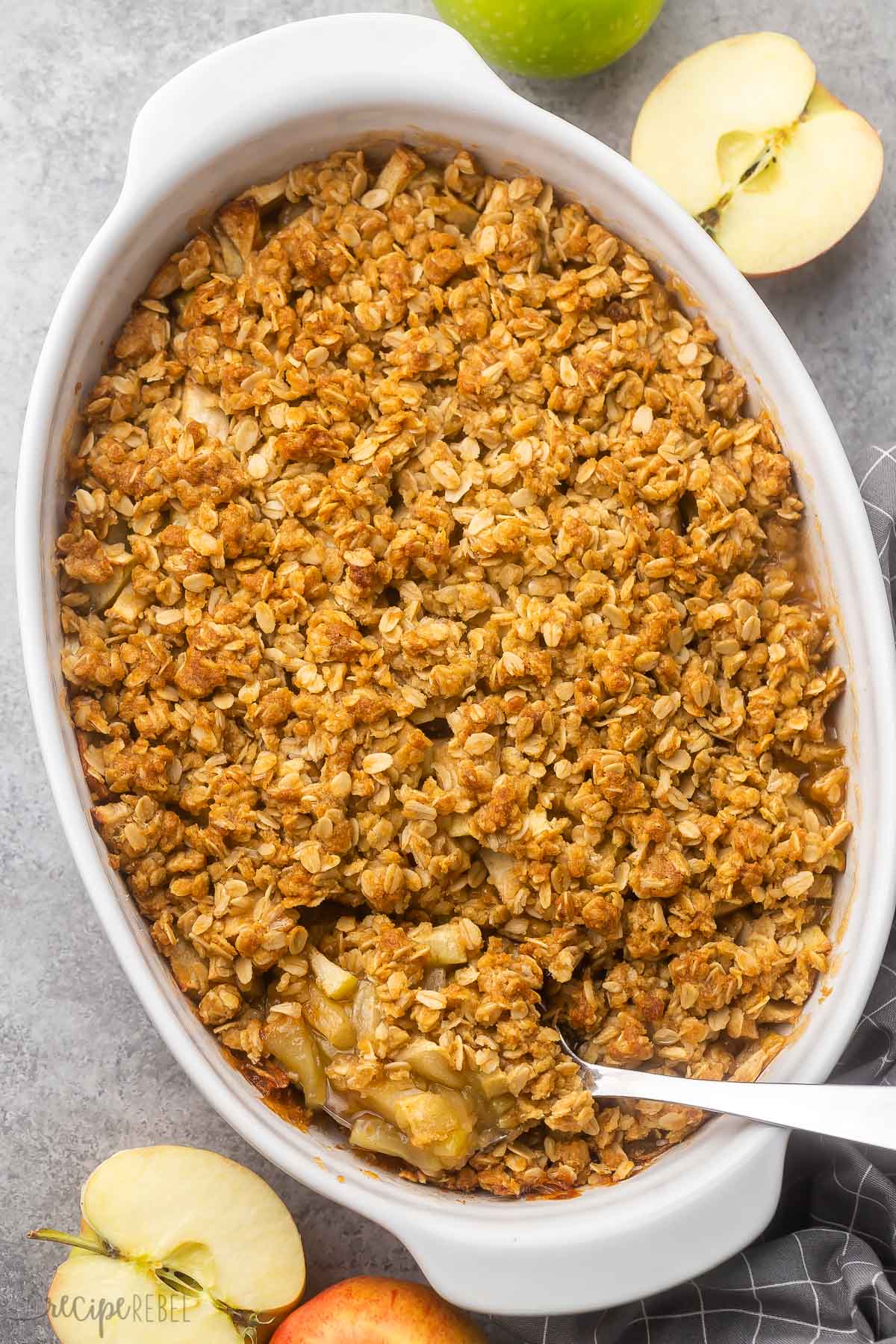 baking dish of freshly baked apple crisp with apples beside.