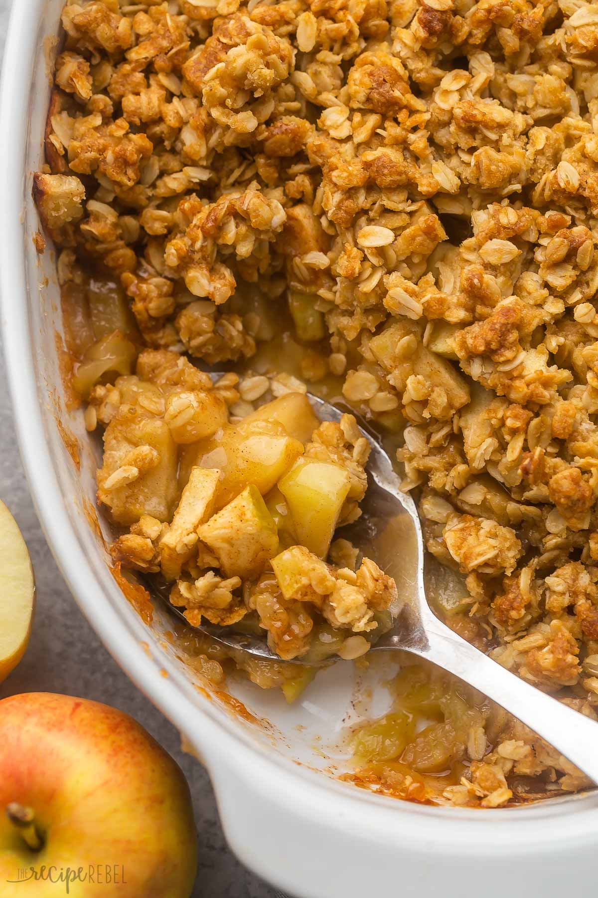 close shot of a white dish of apple crisp with a scooped spoon full.