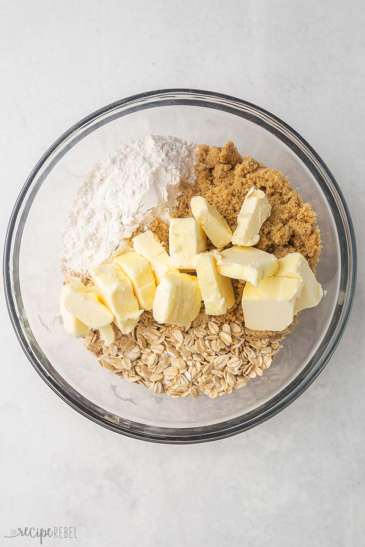 glass bowl with dry ingredients and cubed butter on top.