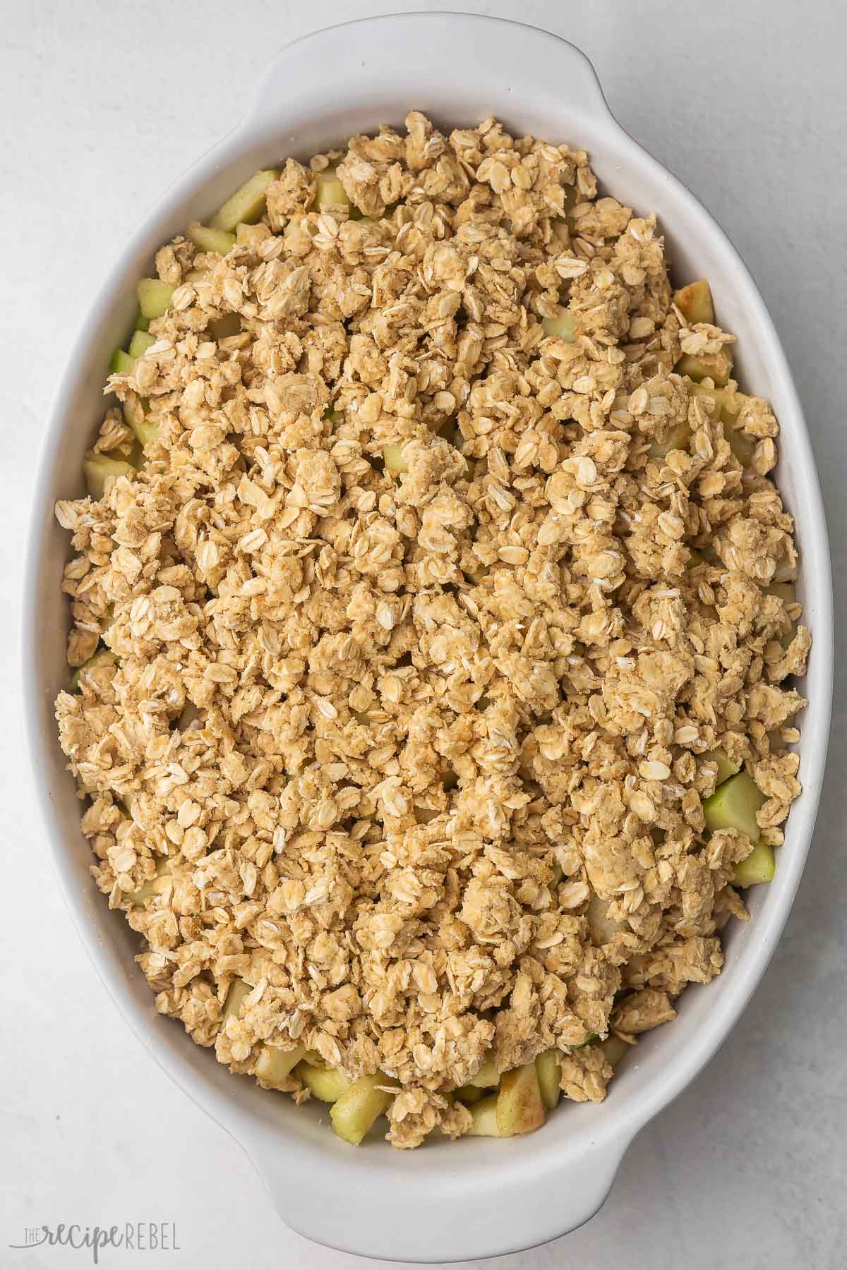white baking dish filled with apple crisp and ready to be baked.