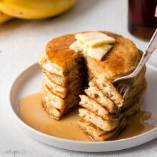 a stack of pancakes on a plate topped with butter and syrup.
