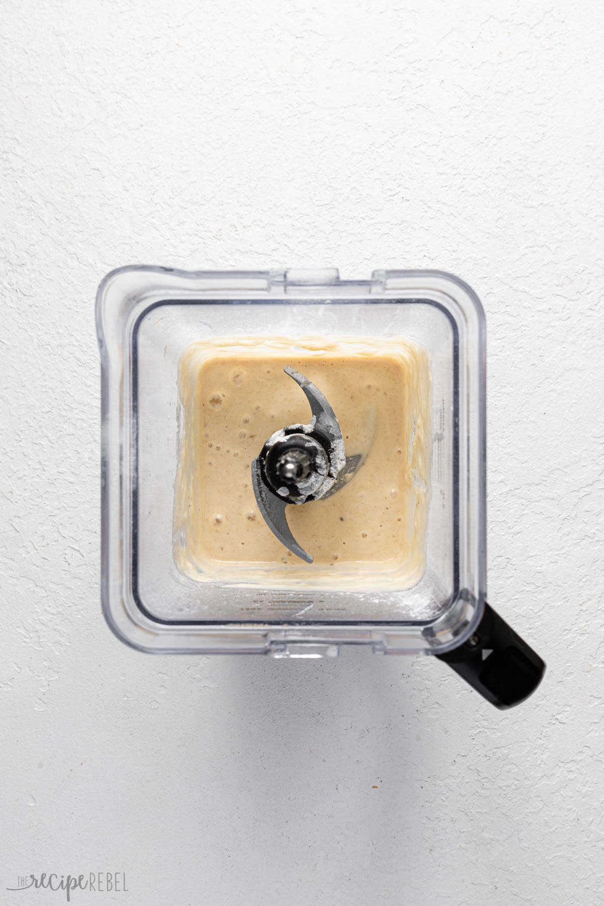 a blender filled with mixed ingredients on a white surface.