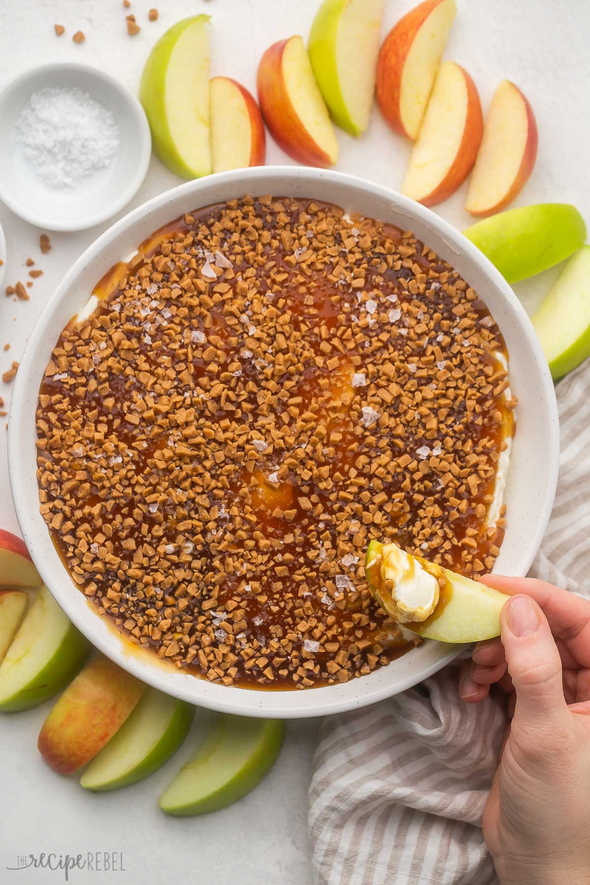 plate of caramel apple dip with apple slice held above.