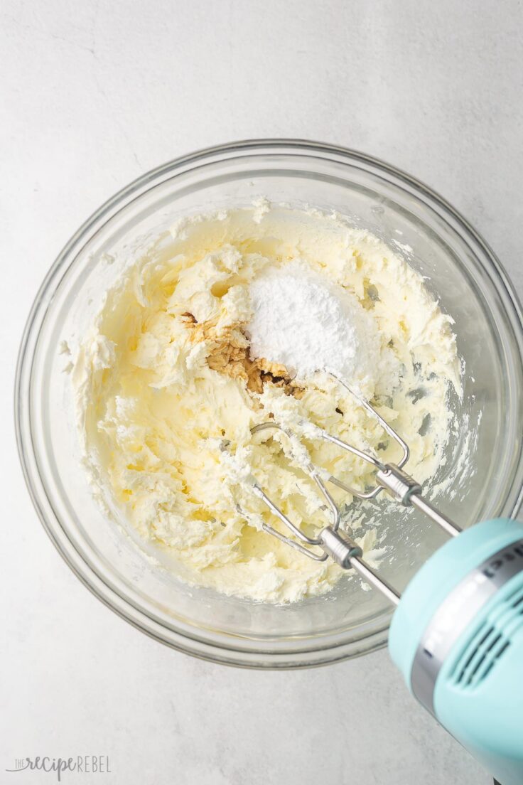 cream cheese and other ingredients in glass bowl with mixer beside.