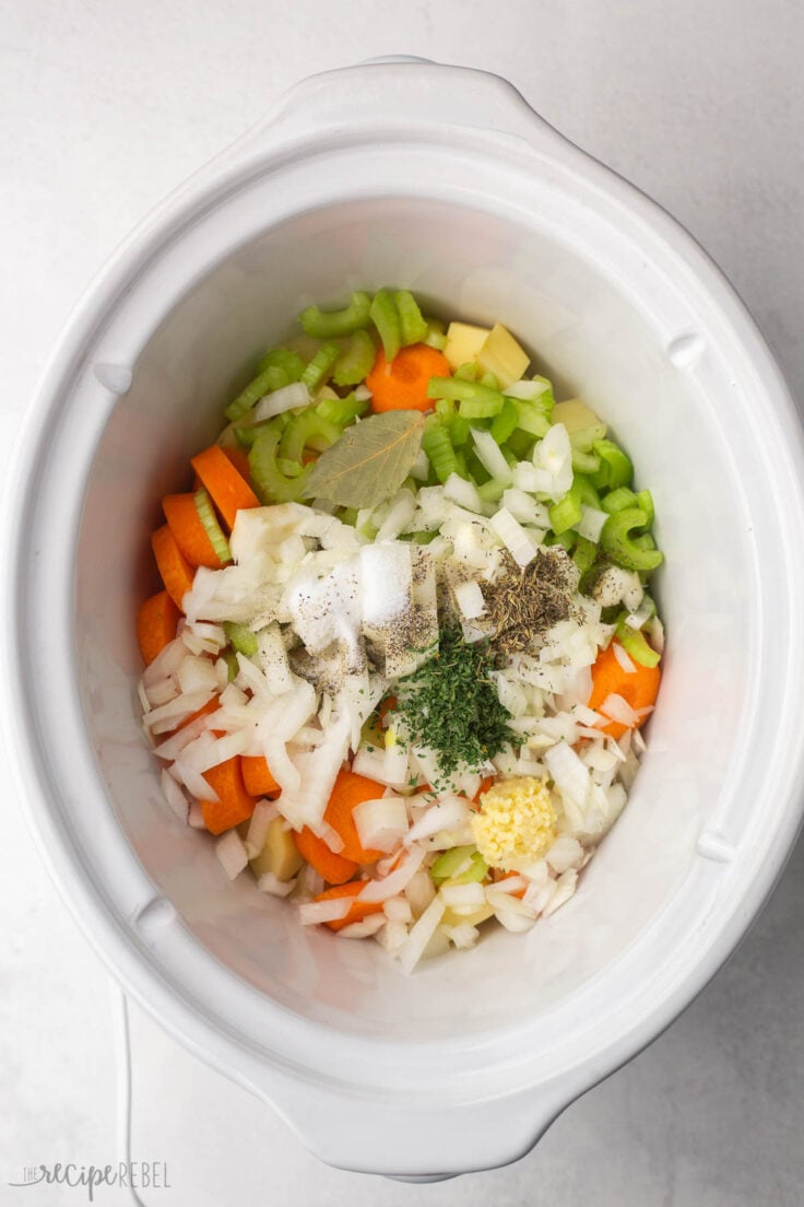 white crockpot full of vegetables and spices.