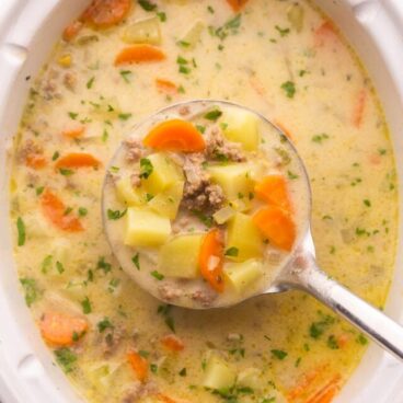 full slow cooker with metal ladle scooping soup out.