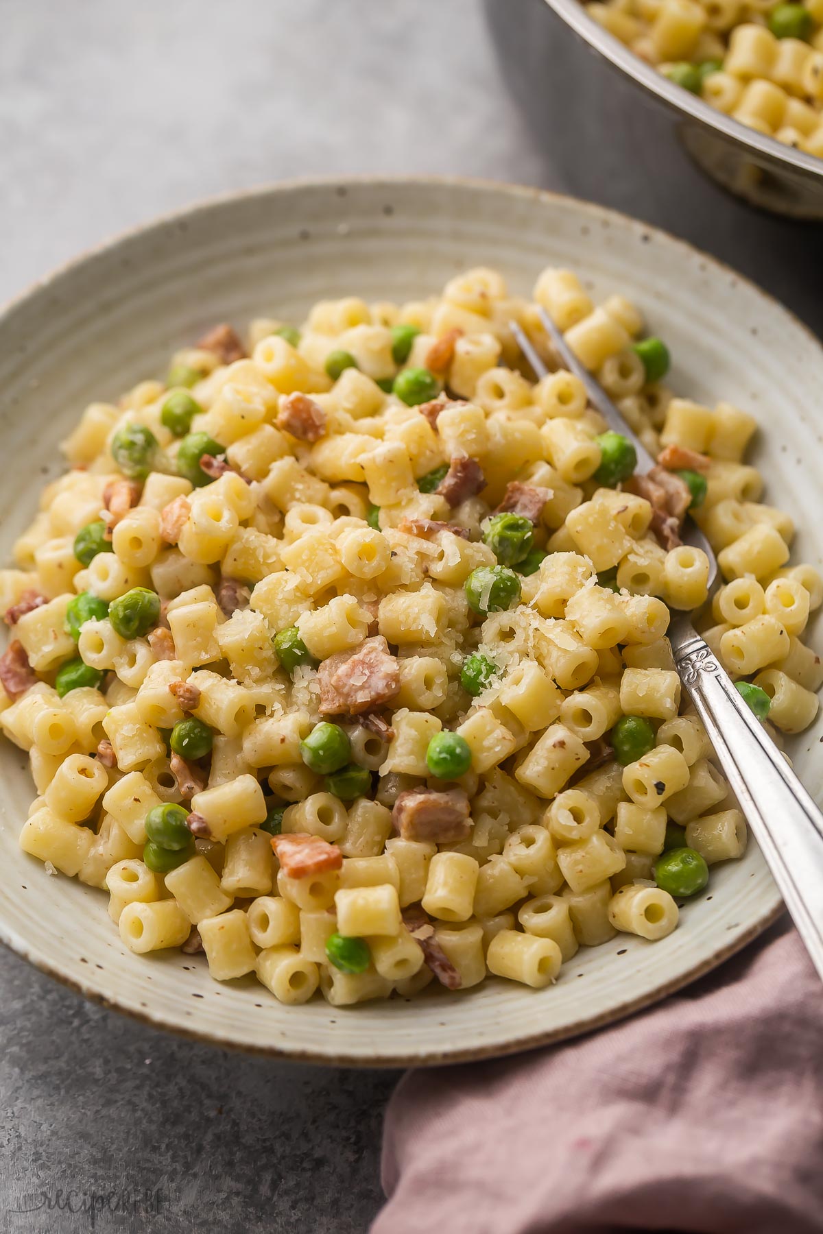 ditalini pasta in grey plate with fork on the side and pan in the background.