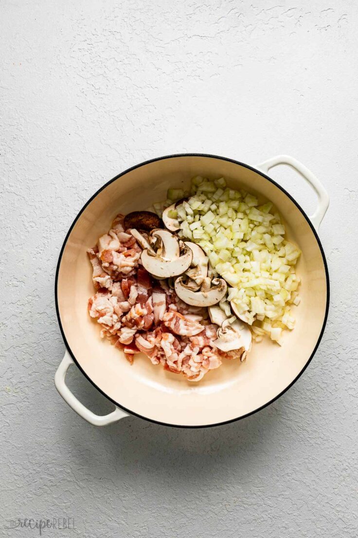 white pot filled with uncooked onions, mushrooms and bacon.