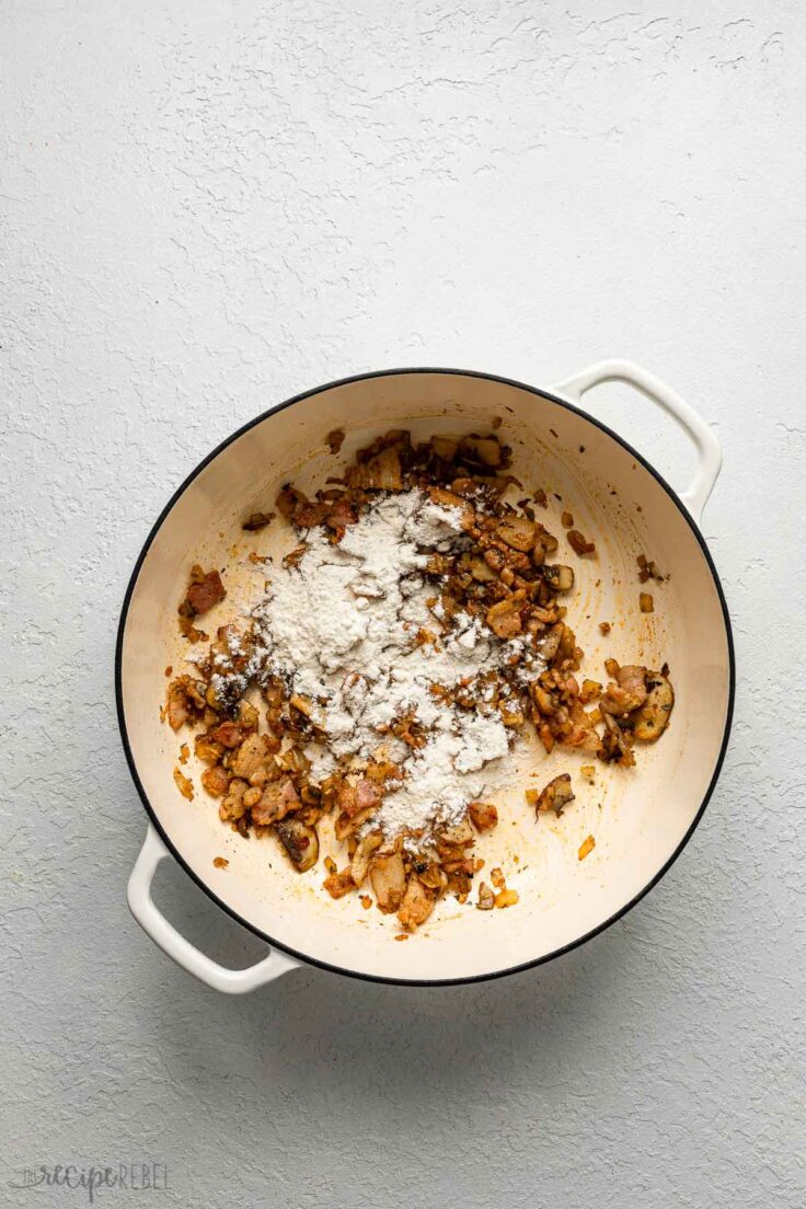 white pot of sauteed ingredients with flour sprinkled on top.