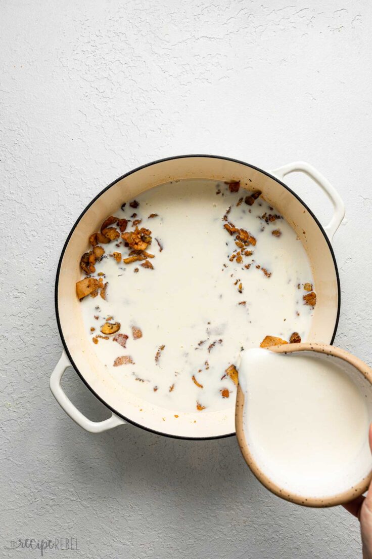 cream being poured into pot of suateed ingredients.